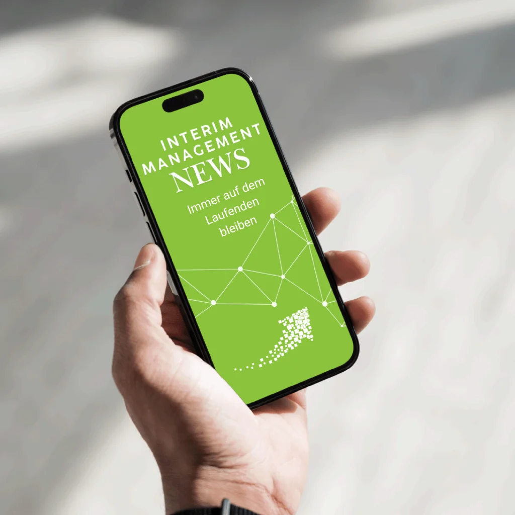 Smartphone mit grünem Bildschirm und der Aufschrift ‚Interim Management News‘ wird von einer Hand gehalten