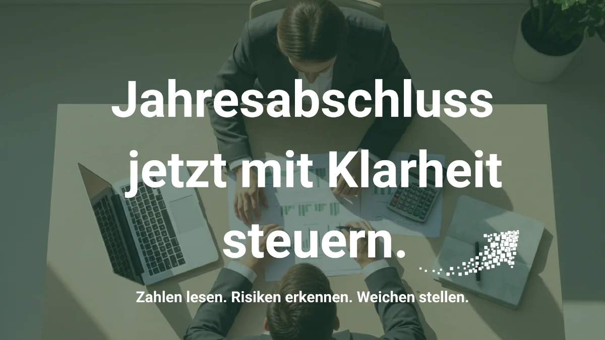 Ein Mann und eine Frau sitzen an einem Schreibtisch mit ausgedruckten Bilanzen und Laptop. Davor steht die Überschrift mit Jahresabschluss jetzt mit Klarheit steuern. 