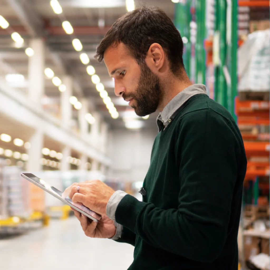 Interim Manager - Digitalisierung Ein Mann steht in einer Lagerhalle mit einem Tablet in der Hand und schaut auf den Bildschirm