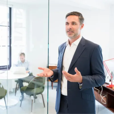 Ein Interim Geschäftsführer steht in einem Büro und erklärt etwas – Symbolbild für Interim Management.