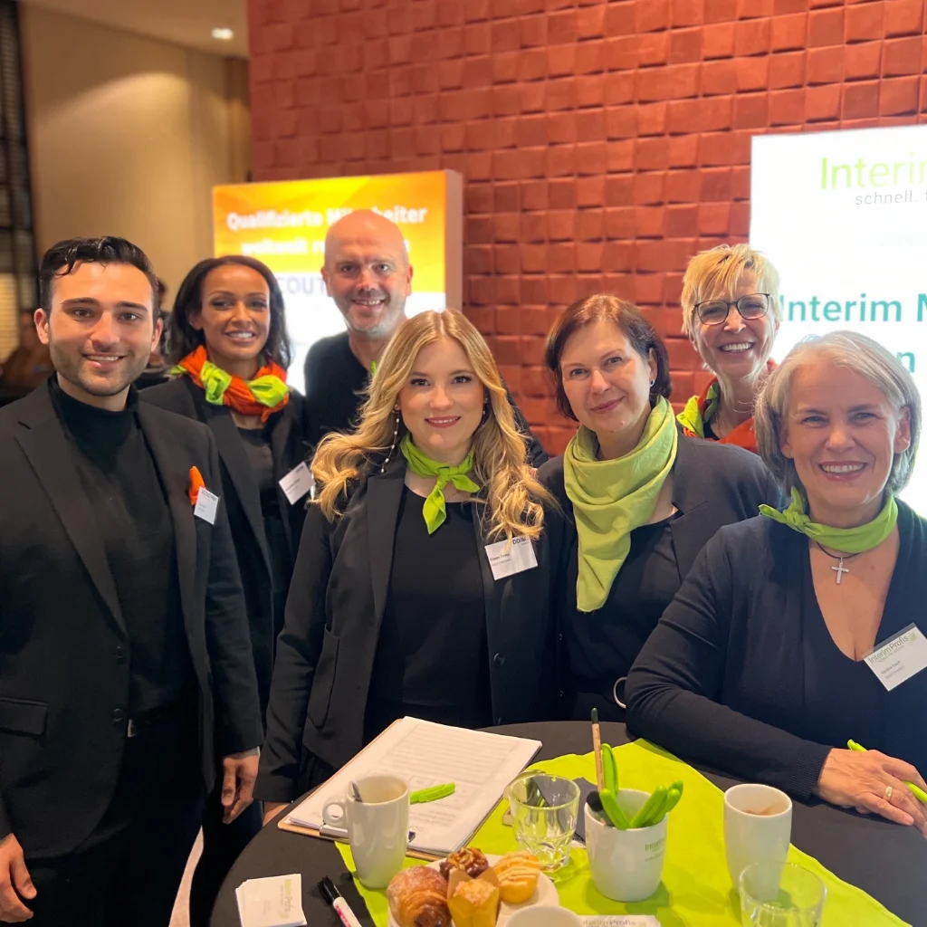 Das Team der Interim Profis und SCOUTMENT stehen gemeinsam an einem Messestand vom DDIM Kongress
